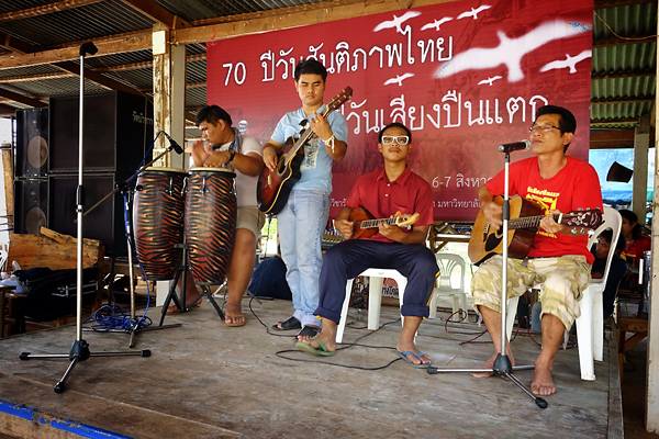 Former village teacher Santayakon Jitmat and students from Sakon Nakhon Rajabhat University perform revolutionary songs on a small stage on the temple ground.